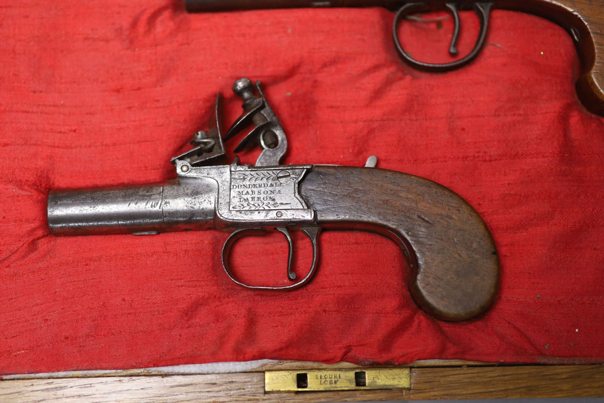 Two 19th century Dunderdale, Mabson & Labron steel flintlock pocket pistols, turn off barrels and walnut butts, in a later oak case